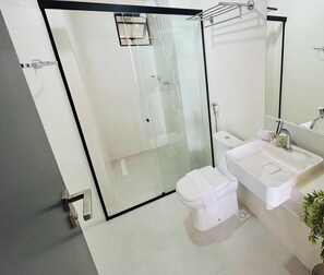 A modern bathroom with a glass shower enclosure, a white toilet, and a sink with a mirror. - LM SUN INTERMARES (Cabedelo)