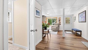 A hallway with wooden flooring, a door, a chair, a bench, and a potted plant. - Summit Sanctuary – Minutes to Downtown Blue Hill! (Blue Hill)