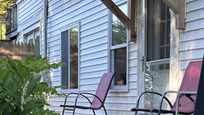 A porch with two chairs, a wooden deck, and flowering plants. - Summit Sanctuary – Minutes to Downtown Blue Hill! (Blue Hill)
