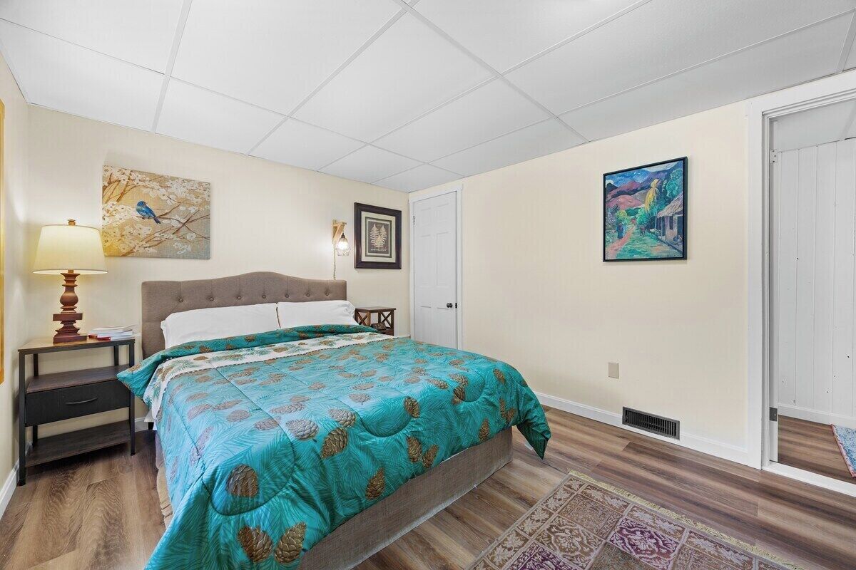 Una camera da letto con un letto, un comodino, una lampada e opere d'arte alle pareti.