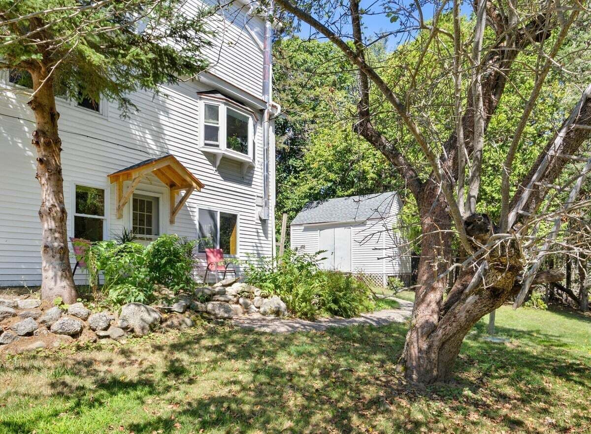 A two-story house with a porch, a small shed, and a well-maintained garden.