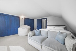 Un dormitorio con cama, sofá, reposapiés blanco y armario.