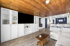 Una sala de estar moderna con suelo de madera, estanterías empotradas blancas, una chimenea y una zona de estar con sofá y sillones.