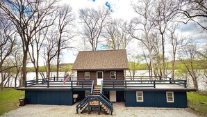 A wooden cabin with a porch, a staircase, and a flag.