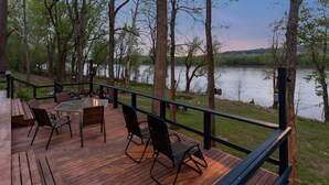 A wooden deck with outdoor furniture, overlooking a lake.
