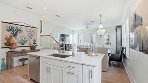 Una cocina moderna con armarios blancos, una isla central y un comedor con candelabro.