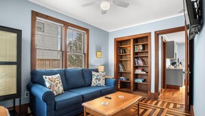 Un salon avec un canapé bleu, une table basse en bois et une bibliothèque.