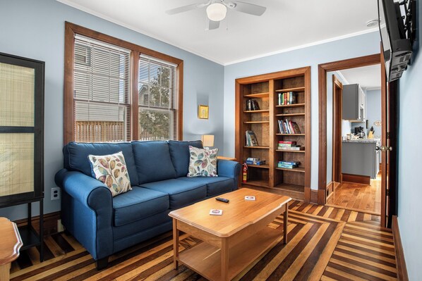 A living room with a blue sofa, wooden coffee table, and a bookshelf.