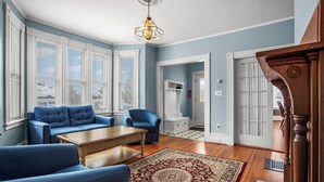 Un salon avec un canapé bleu, une table basse en bois et un tapis à motifs.
