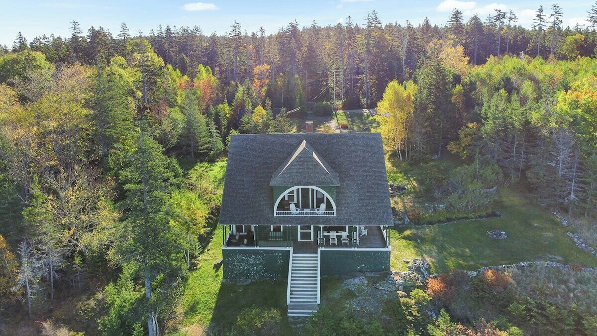 A house with a steep roof, a front porch, and a driveway leading to the entrance.
