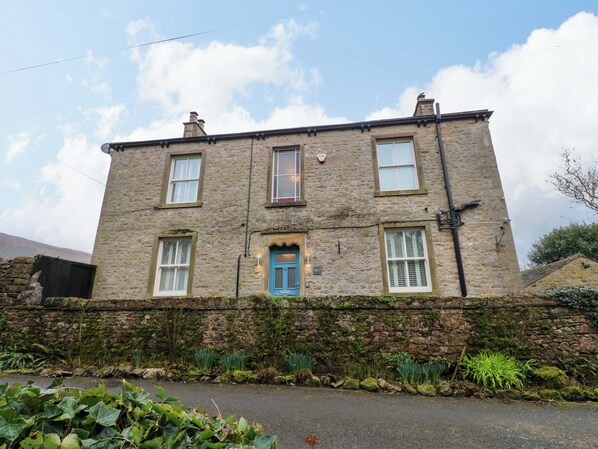 A stone building with a blue door, multiple windows, and a stone wall. - Langcliffe House (Skipton)