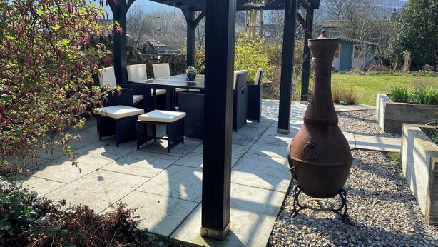 Un patio con mobili da esterno, una pergola e un vaso grande.