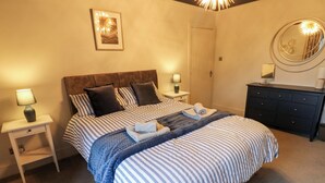 Una camera da letto ordinata con un letto, comodini, una cassettiera e uno specchio fissato alla parete.