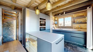 A modern kitchen with a stone wall, wooden beams, and a large window. - Chalou LUXE & COSY chalet 8 personnes (Hérémence)