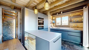A modern kitchen with a stone wall, wooden beams, and a large window. - Chalou LUXE & COSY chalet 8 personnes (Hérémence)