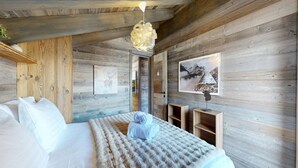 A wooden cabin bedroom with a bed, a fluffy blanket, a hanging light fixture, and framed pictures on the walls. - Chalou LUXE & COSY chalet 8 personnes (Hérémence)