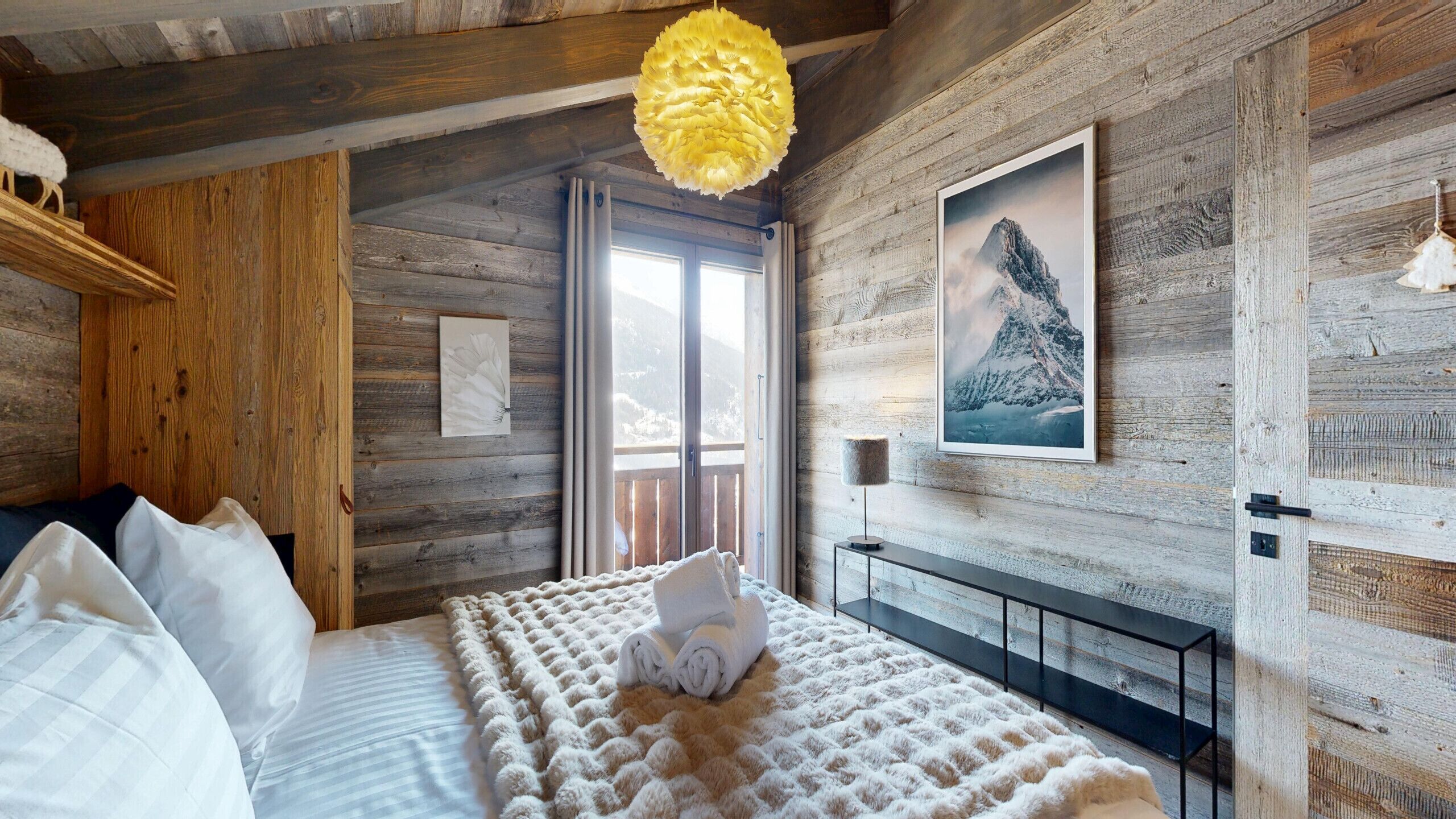 Una stanza rustica in legno con un letto, un lampadario e un quadro appeso al muro.
