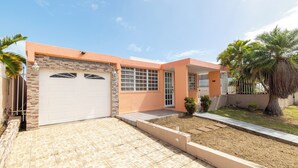 Ein Wohnhaus mit Garage, einem gepflasterten Auffahrt und einem kleinen Garten mit Palmen.