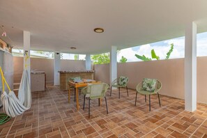 An outdoor patio with a table and chairs, a hanging hammock, and a bamboo fence. - Casita de Papi - Near Beach and Rainforest (luquillo)