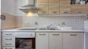 A kitchen with a built-in oven, a stainless steel range hood, and light wood cabinets.