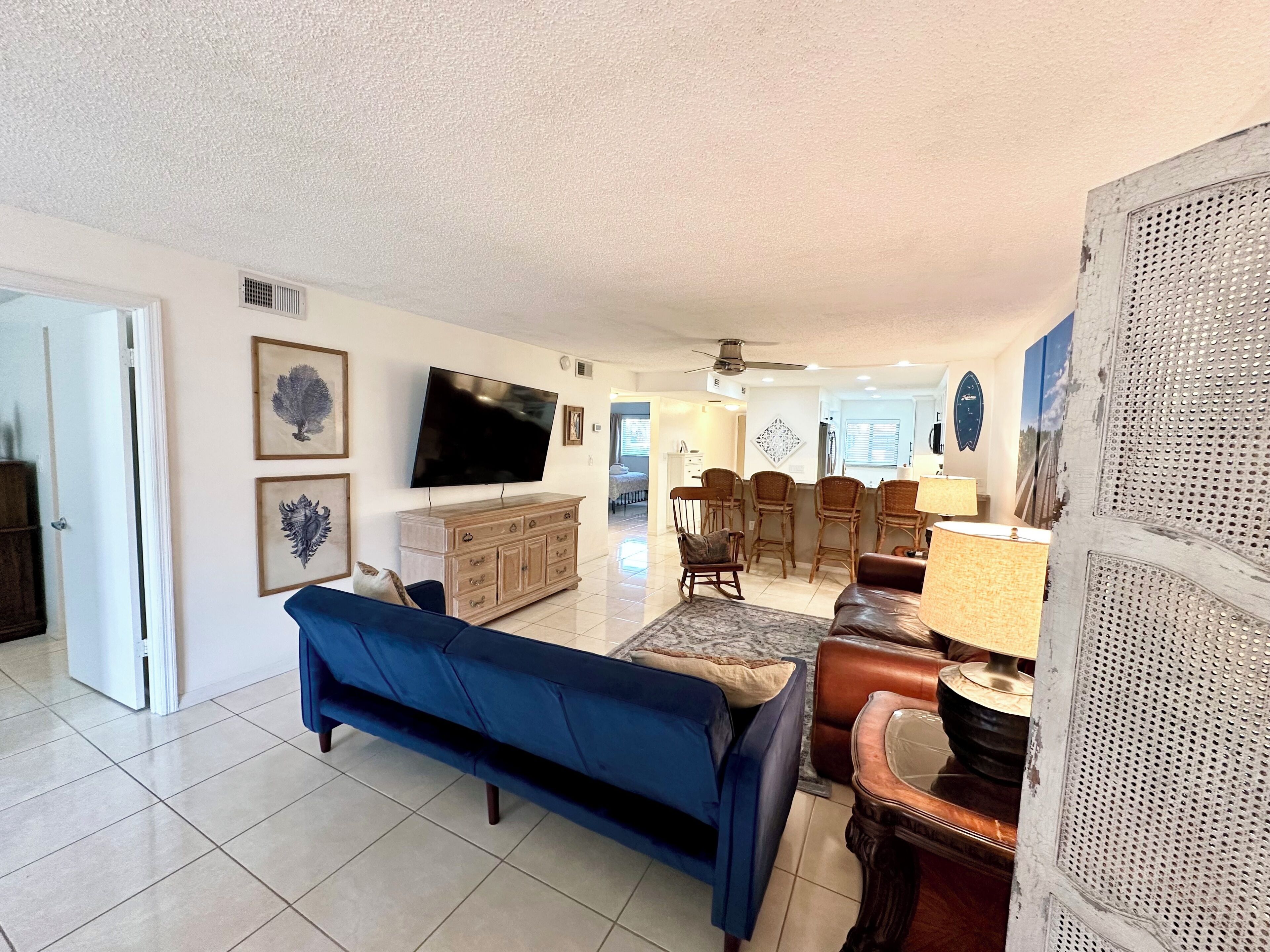 A living room with a blue sofa, a wooden cabinet, a television, and a dining area with chairs.