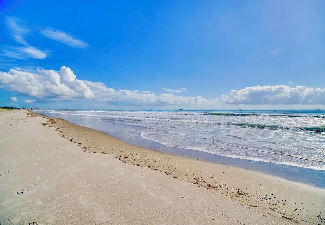 A beach with a sandy shore and waves.