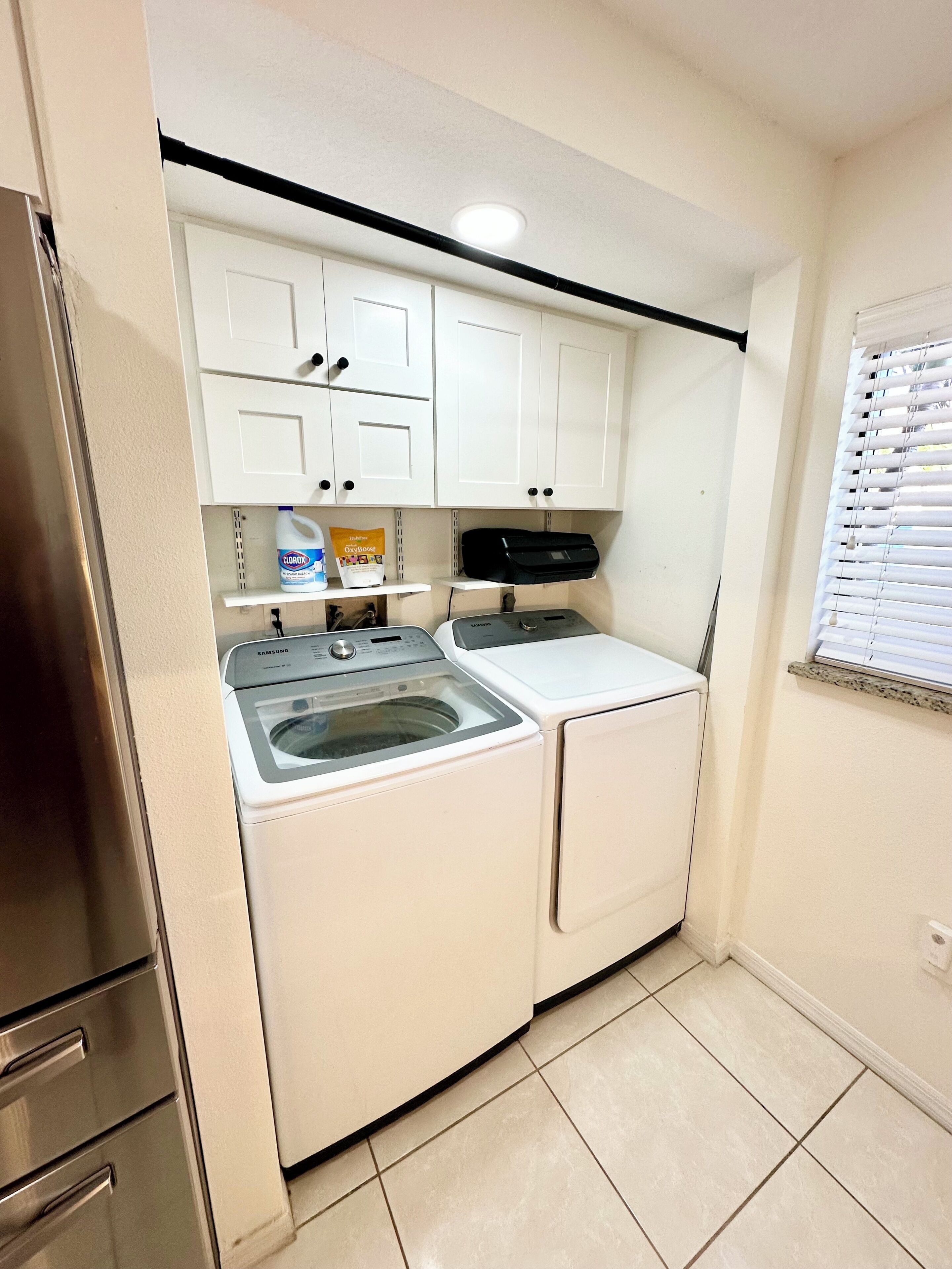 Una cocina compacta con lavadora, una secadora Samsung y refrigerador.