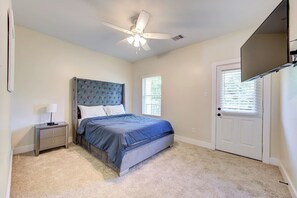 Ein Schlafzimmer mit Bett, Nachttisch, Deckenventilator, Tür und Fenster.