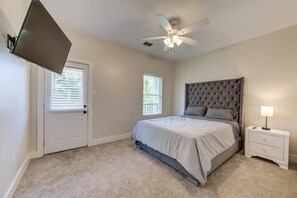 A bedroom with a bed, a nightstand, a TV mounted on the wall, and a ceiling fan. - Urban Retreat Houston- 9 Min from Downtown, Unit B (Houston)