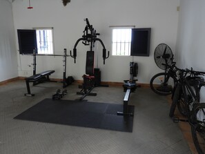 A gym with exercise equipment, a bench, a fan, and a bicycle. - Hacienda Célèbre, Curaçao (Jan Thiel)