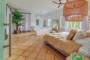 A bedroom with a bed, a ceiling fan, a potted plant, and a window. - Hacienda Célèbre, Curaçao (Jan Thiel)