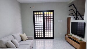 A living room with a sofa, TV, and tiled floor. - House (two-story house) for 9 people, very close to MotoGP. (Goiânia)