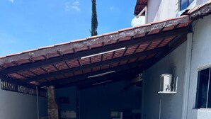 A covered patio area with tiled flooring, a brick chimney, and a white air conditioning unit mounted on the wall. - House (two-story house) for 9 people, very close to MotoGP. (Goiânia)