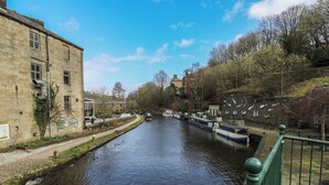 A river with boats, a bridge, and buildings along the banks. - Green Route Apartment (Todmorden)
