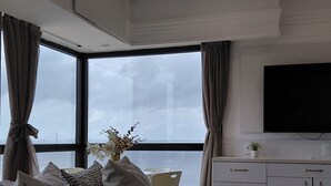 Une chambre moderne avec un grand lit, une télévision et une vue sur la mer.