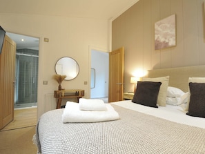 A hotel room with a bed, a bedside table, a mirror, a shower, and a door leading to another room. - 4 Southern Place (Liskeard)