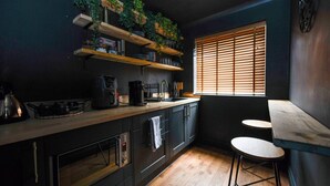 A kitchen with dark cabinetry, wooden countertops, a built-in stove, and a window with blinds. - Bold boudoir interiors, private patio and steps from the beach (West Sussex)