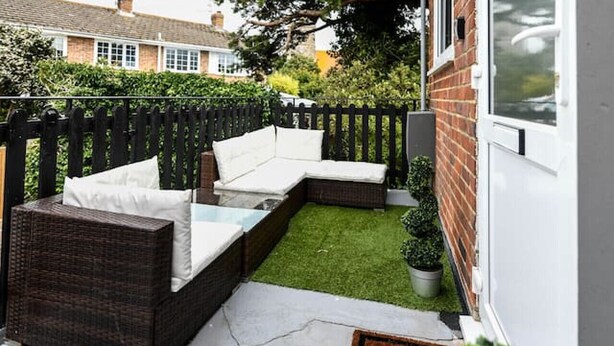 A patio with a built-in seating area, a small lawn, and a brick wall. - Bold boudoir interiors, private patio and steps from the beach (West Sussex)