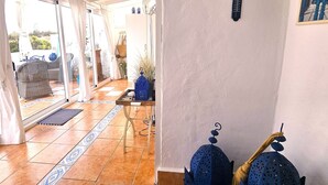 Quarto com piso de azulejos, um relógio de parede, termômetro e uma moldura com imagem.