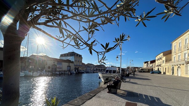 Paseo marítimo con un barco amarrado, bancos y edificios a lo largo del agua.