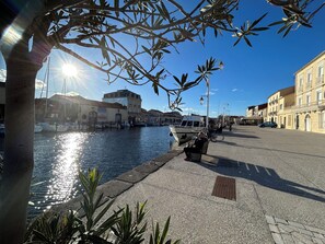 Eine Uferpromenade mit vertäutem Boot, Bänken und Gebäuden am Wasser.