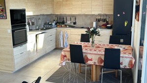 Una cocina moderna con armarios de madera, una mesa de comedor con sillas y un refrigerador.