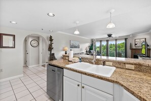 A kitchen with granite countertops, a white sink, and a clock on the wall. - Golf Vista 171 with Balcony (Pigeon Forge)
