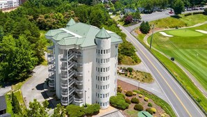 Un hôtel à plusieurs étages, doté d’une tour centrale, entouré de verdure et d’un parcours de golf.