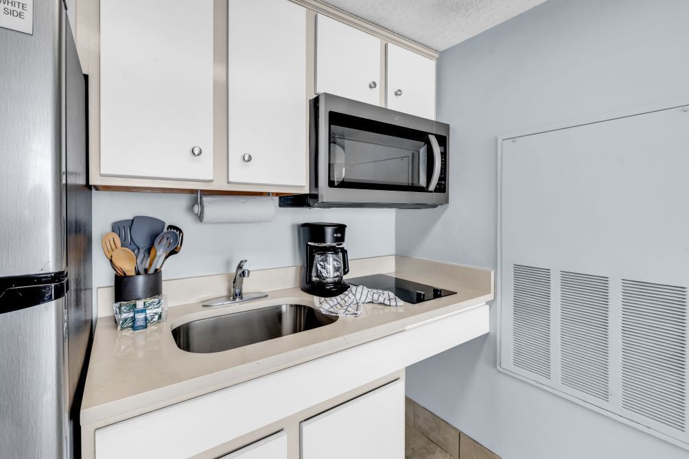 A kitchen with a stainless steel refrigerator, a microwave, a coffee maker, and a sink.