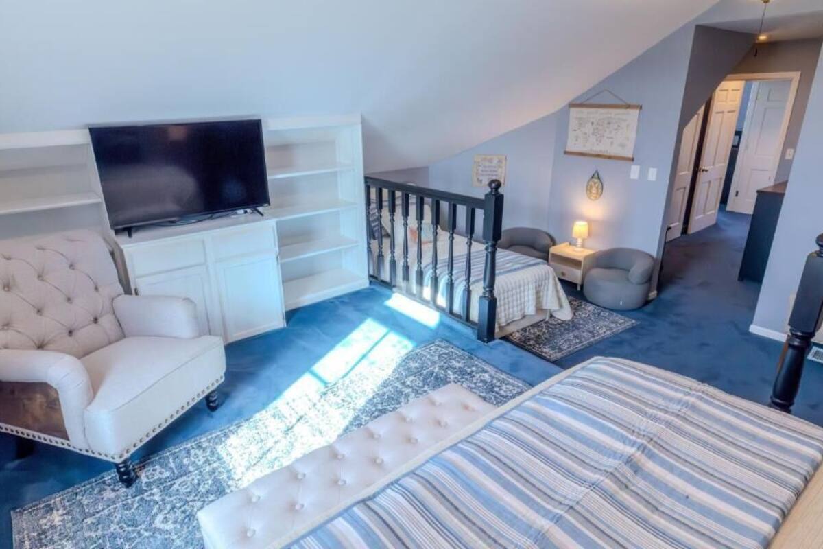 Quarto com uma cama grande, televisão, sofá e escada.