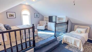 A bedroom with a bed, a chair, a television, and a staircase.