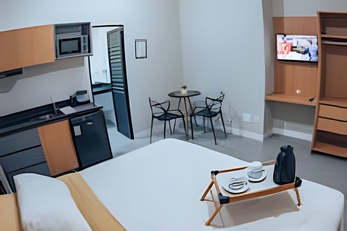 A modern hotel room with a bed, desk, chair, TV, and a small dining table.