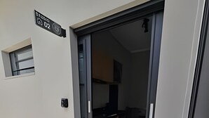 A modern apartment entrance with a sliding glass door leading to a kitchen area. - Zuccaro Studio (Bauru)