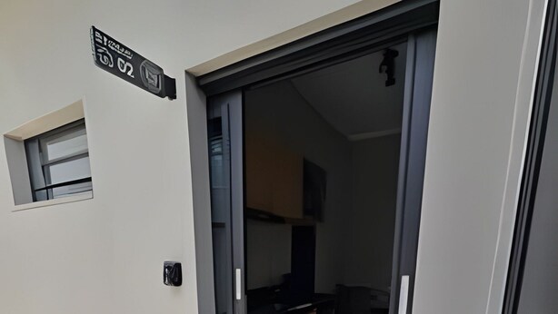 Entrada de un apartamento moderno con puerta corredera de vidrio que da a una zona de cocina.